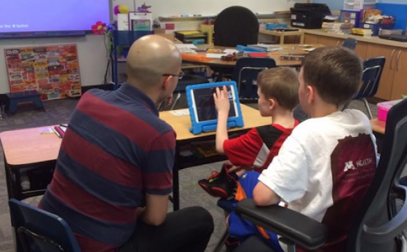 CTEP member assists a boy using an ipad in a classroom.