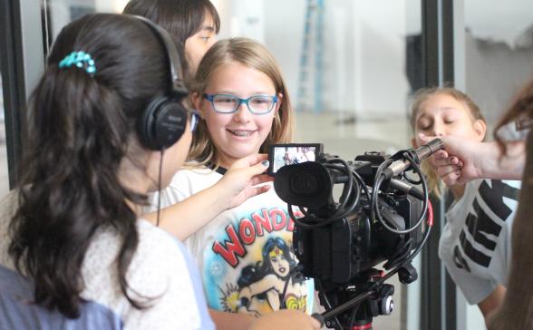 A photograph of three girl scouts using a camera. 