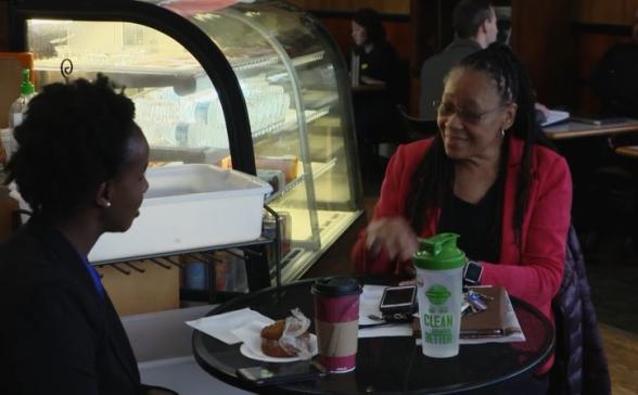 two women sitting at a small round table in a coffee shop.